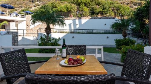 a table with a plate of fruit and a bottle of wine at Sirene Beach Hotel in Ixia