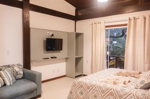 a bedroom with a bed and a tv and a couch at Flat Bouganville in Abraão