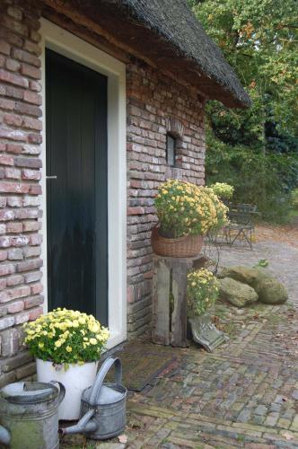 a brick house with two potted plants next to a door at B&B Onze Deel in Hijken