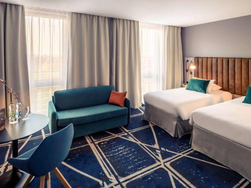 une chambre d'hôtel avec deux lits et une chaise dans l'établissement Hotel Mercure Poznań Centrum, à Poznań