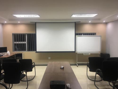 a meeting room with a large projection screen and chairs at The Afropolitan in Johannesburg