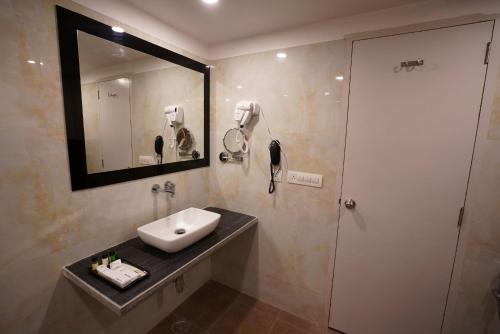 a bathroom with a sink and a shower with a mirror at Hotel Indo Prime in Jaipur