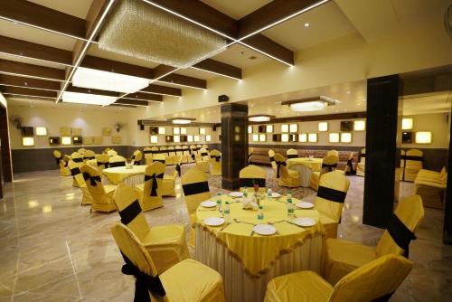 a banquet hall with tables and yellow chairs at Hotel Indo Prime - Jaipur City Centre in Jaipur