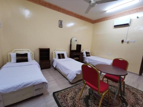 a room with two beds and a table and chairs at Salassel Al Jabal Al Akhdar Guesthouse in Al ‘Aqar