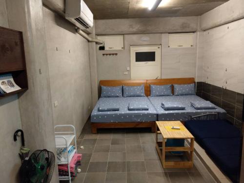 Un pequeño dormitorio con una cama azul y una mesa en 蘭嶼老鍋蓋民宿, en Lanyu