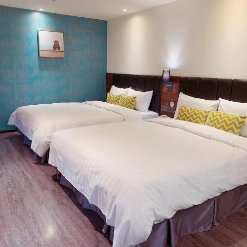 two beds in a hotel room with white sheets at Goldinn Hotel in Taipei