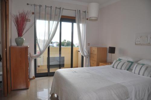 a bedroom with a bed and a large window at SOMAR Torre de Medronheira OLHOS DE AGUA ALBUFEIRA in Olhos de Água