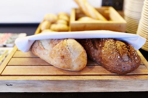 two loaves of bread on a cutting board with french fries at Koszary Arche Hotel in Góra Kalwaria