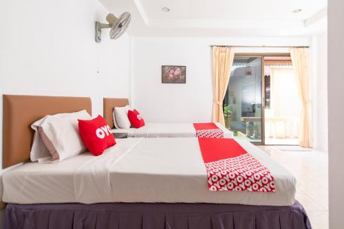 a bedroom with two beds with red and white pillows at OYO 325 Naiyang Cottage in Nai Yang Beach