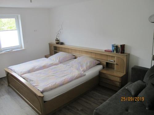 Bett mit einem Kopfteil aus Holz in einem Zimmer in der Unterkunft Gästezimmer 1 mit Bad in Angersbach