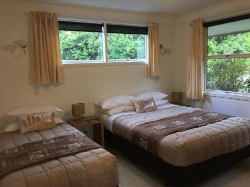 a bedroom with two beds and two windows at Aoraki Alpine Chalet in Mount Cook Village