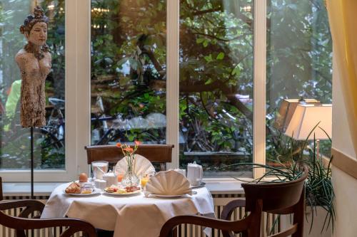 uma mesa num restaurante com uma mulher de pé numa janela em Hotel Olympic em Munique
