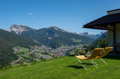 two chairs sitting on top of a hill with mountains at Chalet Alpina in Ortisei