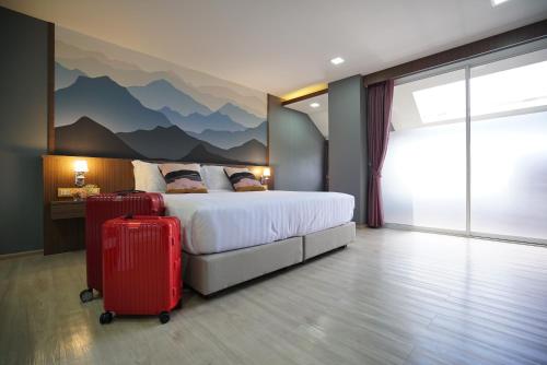 a hotel room with a bed and two suitcases at The Qube fifty Hotel in Bangkok