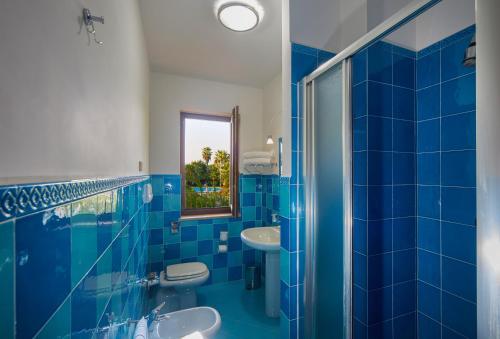 Baño azul con 2 lavabos y espejo en Minerva Resort Hotel, en Paestum