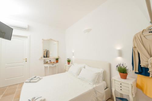 a white bedroom with a bed and a mirror at Masseria Monache in San Pietro Vernotico