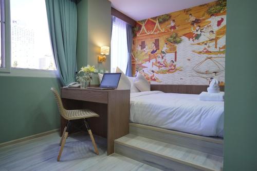 a bedroom with a bed and a desk with a laptop at The Qube fifty Hotel in Bangkok
