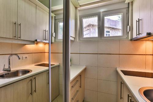 a kitchen with white cabinets and a sink and windows at Zelen LUX in Sutomore