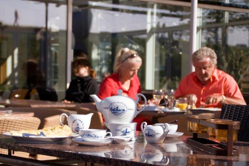 a man and woman sitting at a table with a tea pot at Hotel Regina Maris in Norddeich