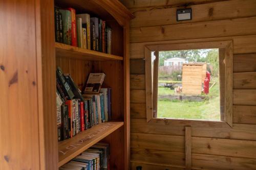 uma janela numa biblioteca de madeira com livros em The Moat Lake Glamping Pod em Clare