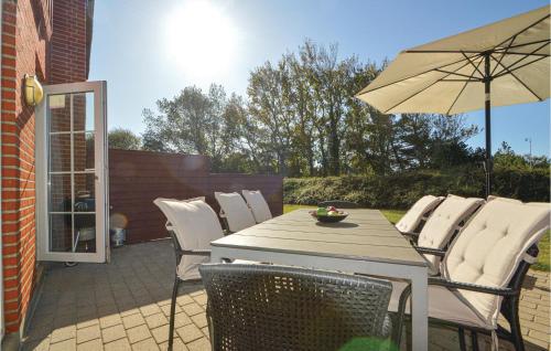 a table and chairs with an umbrella on a patio at Lovely Home In Rømø With House Sea View in Kongsmark