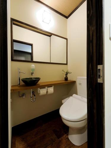 a bathroom with a toilet and a sink and a mirror at Koyado Enn in Toyooka
