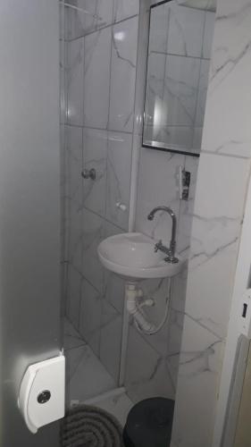 uma casa de banho branca com um lavatório e um chuveiro em Pousada vithoria em Pinhais