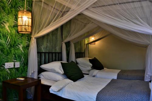 a bedroom with two beds and a canopy at Mitengo House in Lilongwe