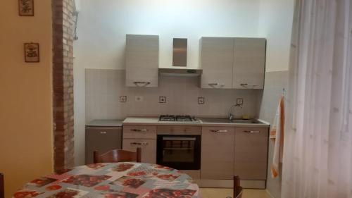 a kitchen with white cabinets and a table and a sink at Casa Vacanza Il Leonpardo in Tuscania