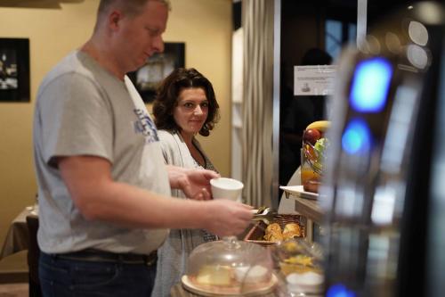 a man and a woman standing next to a counter with a coffee cup at Cit'Hotel La Résidence in Nancy