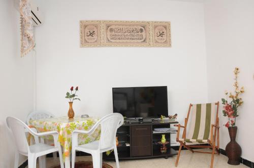 City Apartment Rades Tunis free Wifi في Radès: غرفة طعام مع طاولة وكراسي وتلفزيون