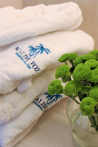 a pile of towels and a vase with a plant at Malibu Foz Hotel - La Maison Younan in Figueira da Foz