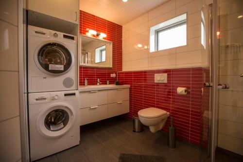 a bathroom with a washer and a toilet and red tiles at Hestasport Apartment in Varmahlid