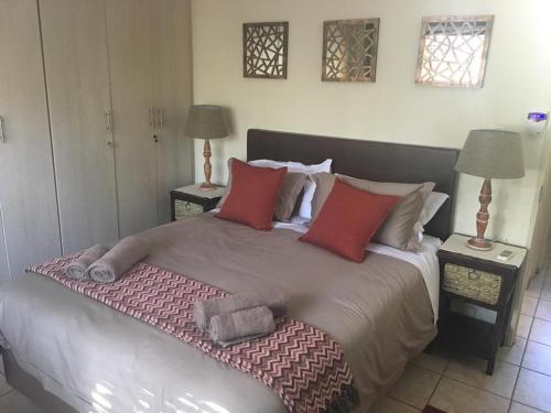 a bedroom with a large bed with red pillows at Villa Danamara in Phalaborwa