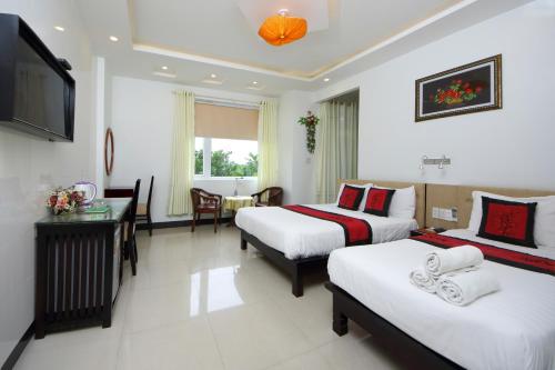a hotel room with two beds and a desk at Flame Flowers Homestay in Hoi An