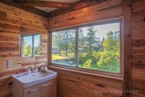 a bathroom with a sink and a large window at Powder Peaks Chalet in Akakura