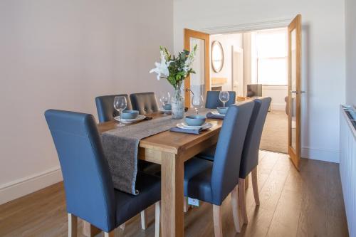 a dining room table with blue chairs and a vase of flowers at 35 High Street Apartment in Hawick