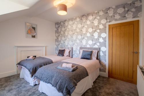 a bedroom with two beds and a wall with flowers at 35 High Street Apartment in Hawick