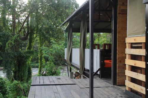 a porch of a house with a wooden deck at hornbill river camp udawalwa in Udawalawe