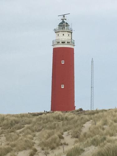 a red and white lighthouse sitting on top of a hill at Ferienhaus am Meer mit Kamin & Sauna - Seestern 251 in Julianadorp