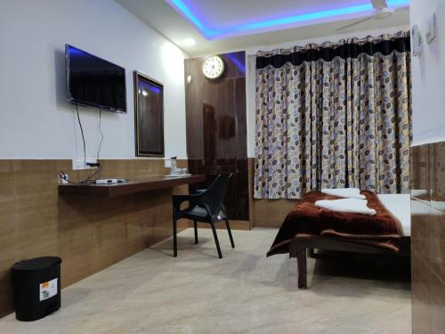 カライクディにあるHotel Sugam Karaikudiのベッドと机とテレビのある部屋
