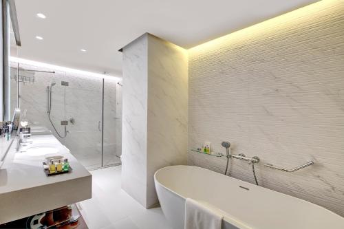 a bathroom with a tub and a sink and a shower at Millennium Place Barsha Heights Hotel in Dubai