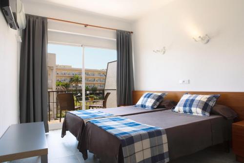 a bedroom with a bed and a large window at Hostal Villa Catí in Paguera