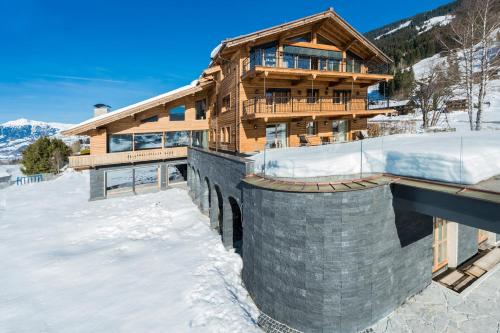 a wooden house in the snow with snow covered at Das Kitz - deLuxe ChaletApartments in Jochberg