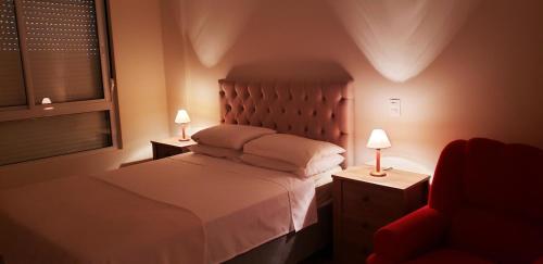 een slaapkamer met een bed en 2 lampen en een stoel bij Residencial Encantos do Mar in Florianópolis