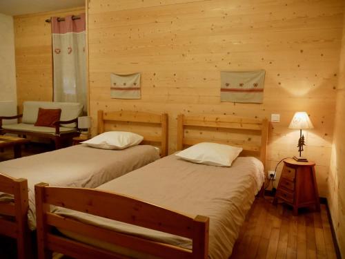 a room with two beds and a chair in a cabin at Ecogite Mercantour Le Chaperon in Valdeblore