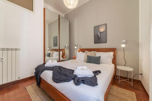 - une chambre avec un lit doté de draps blancs et d'un miroir dans l'établissement Lively Roma Trastevere renovated apartment - FromHometoRome, à Rome