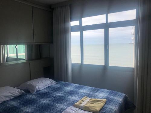 a bedroom with a bed and a large window at Baln Camboriu - Beira mar in Balneário Camboriú