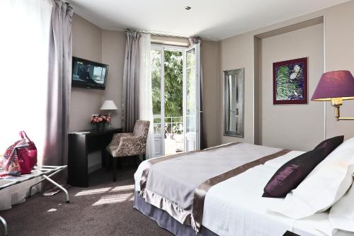 a bedroom with a bed and a desk and a window at La Place Boutique Hotel in Antibes