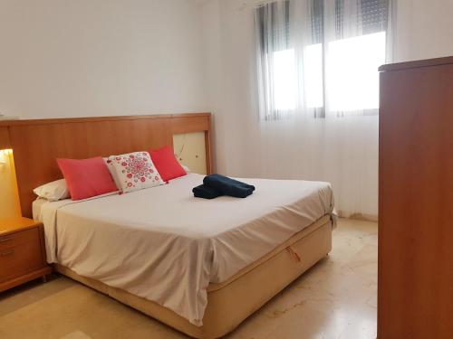 una camera da letto con un grande letto con cuscini rossi di Bel appartement au centre ville et de la plage a Ceuta